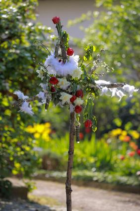 Osterkreuz mit Rosen und Federn geschmückt